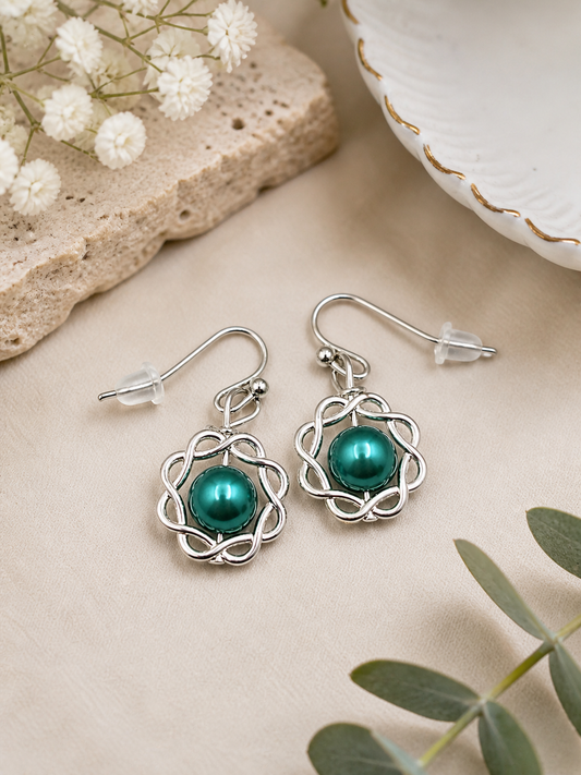 Green pearl swirl earrings styled on neutral background elegant vintage jewelry