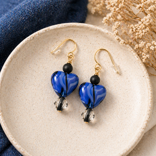 Midnight blue heart earrings styled on ceramic plate with soft background