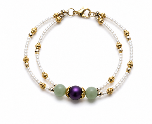Double-strand pearl and gold bracelet with soft green accent beads and royal purple centerpiece on white background