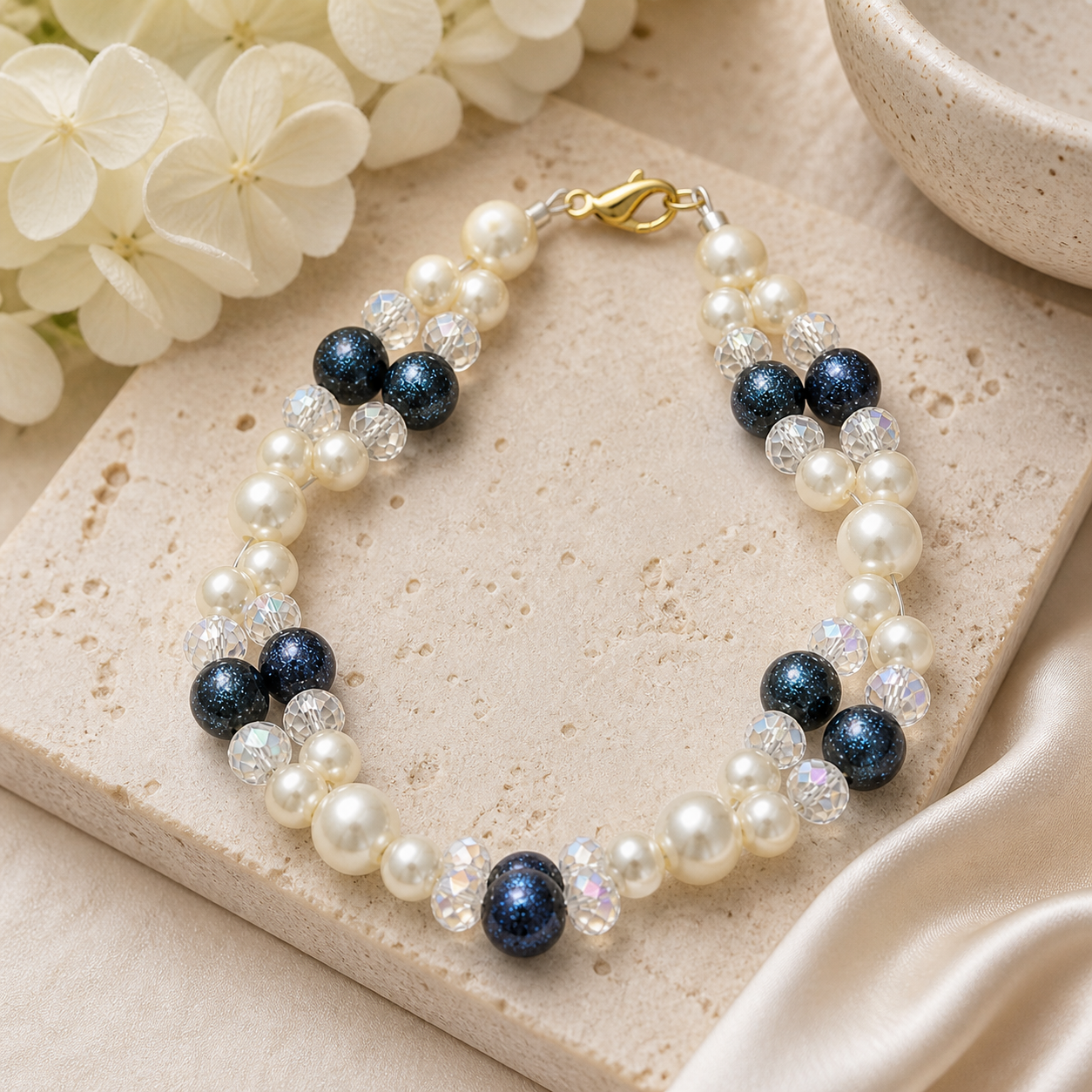 Pearl and navy beaded bracelet styled on neutral stone background elegant handmade jewelry