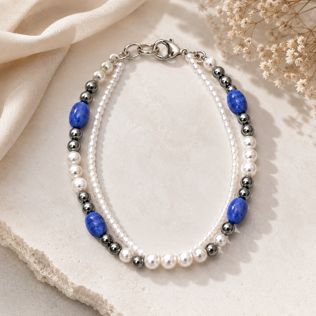 Styled - Elegant handmade dual strand bracelet displayed on a soft neutral styled background with pearls, hematite beads, and blue accent stones in luxury product photography.