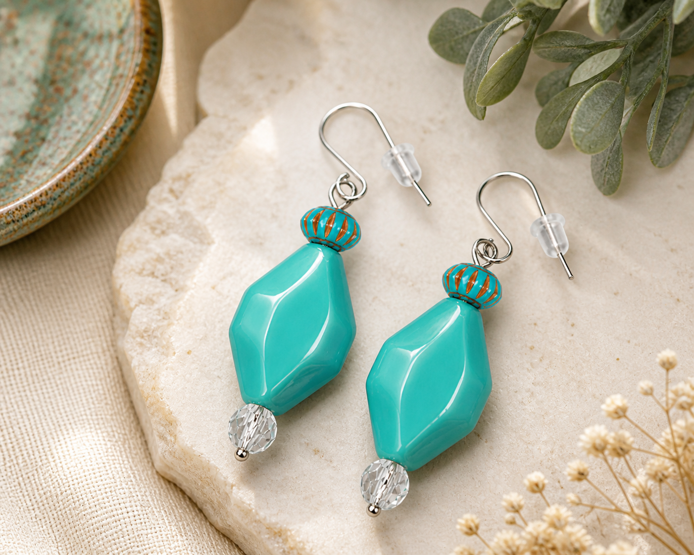 Turquoise boho drop earrings styled on neutral stone background with natural decor