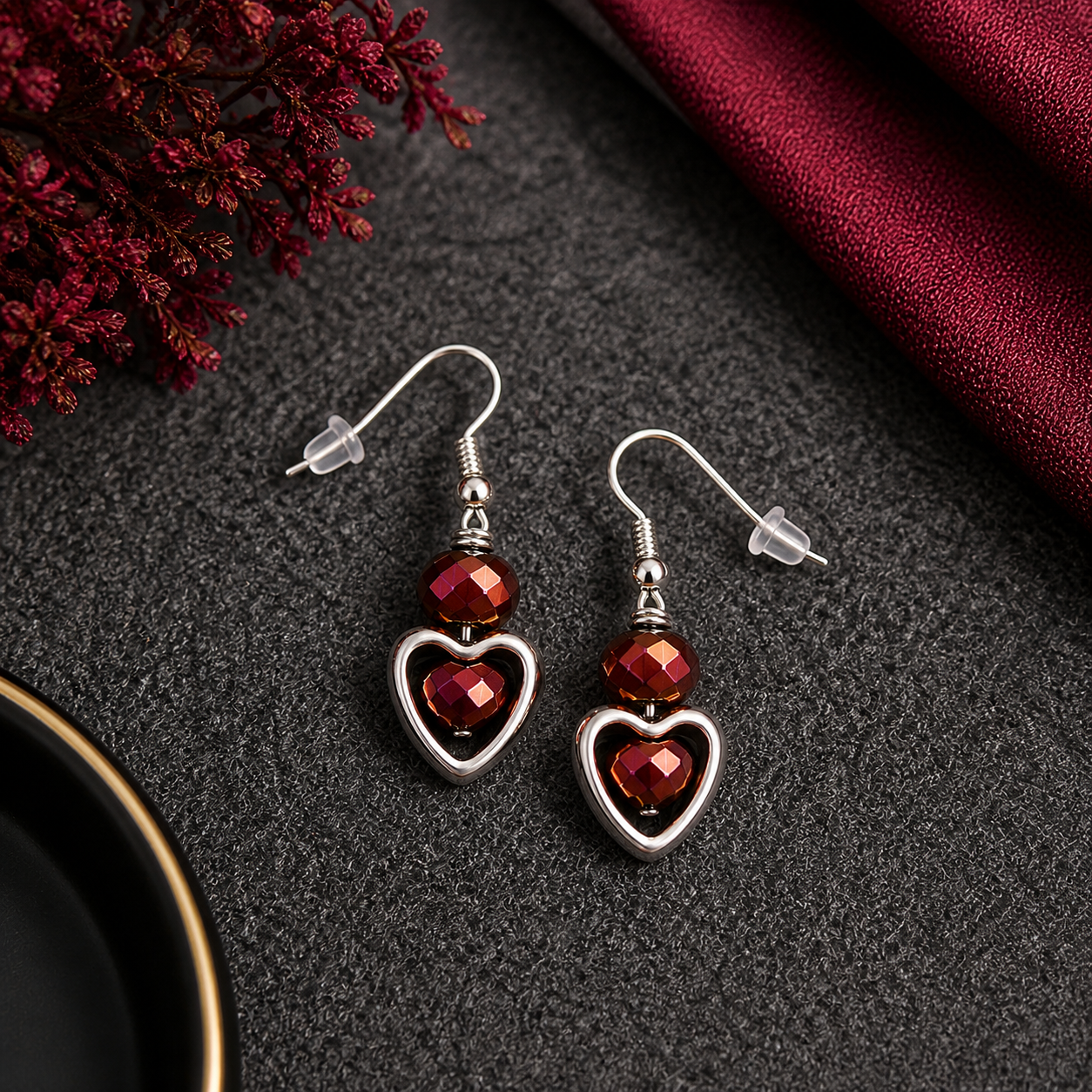 Ruby heart earrings styled on dark fabric with burgundy accents