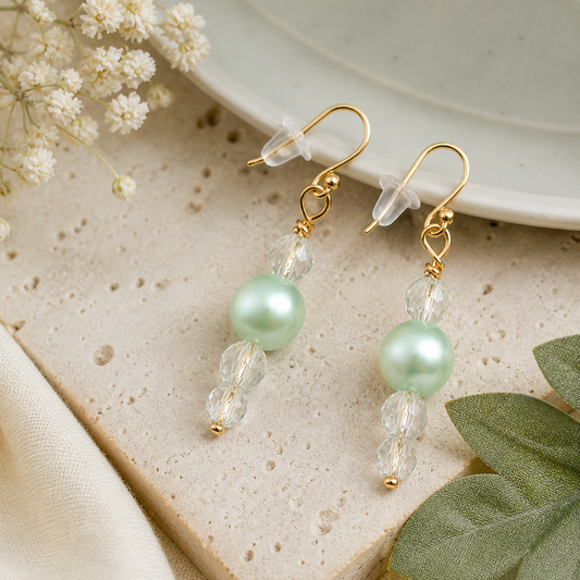 Mint green pearl earrings with crystal beads styled on neutral stone background elegant feminine jewelry