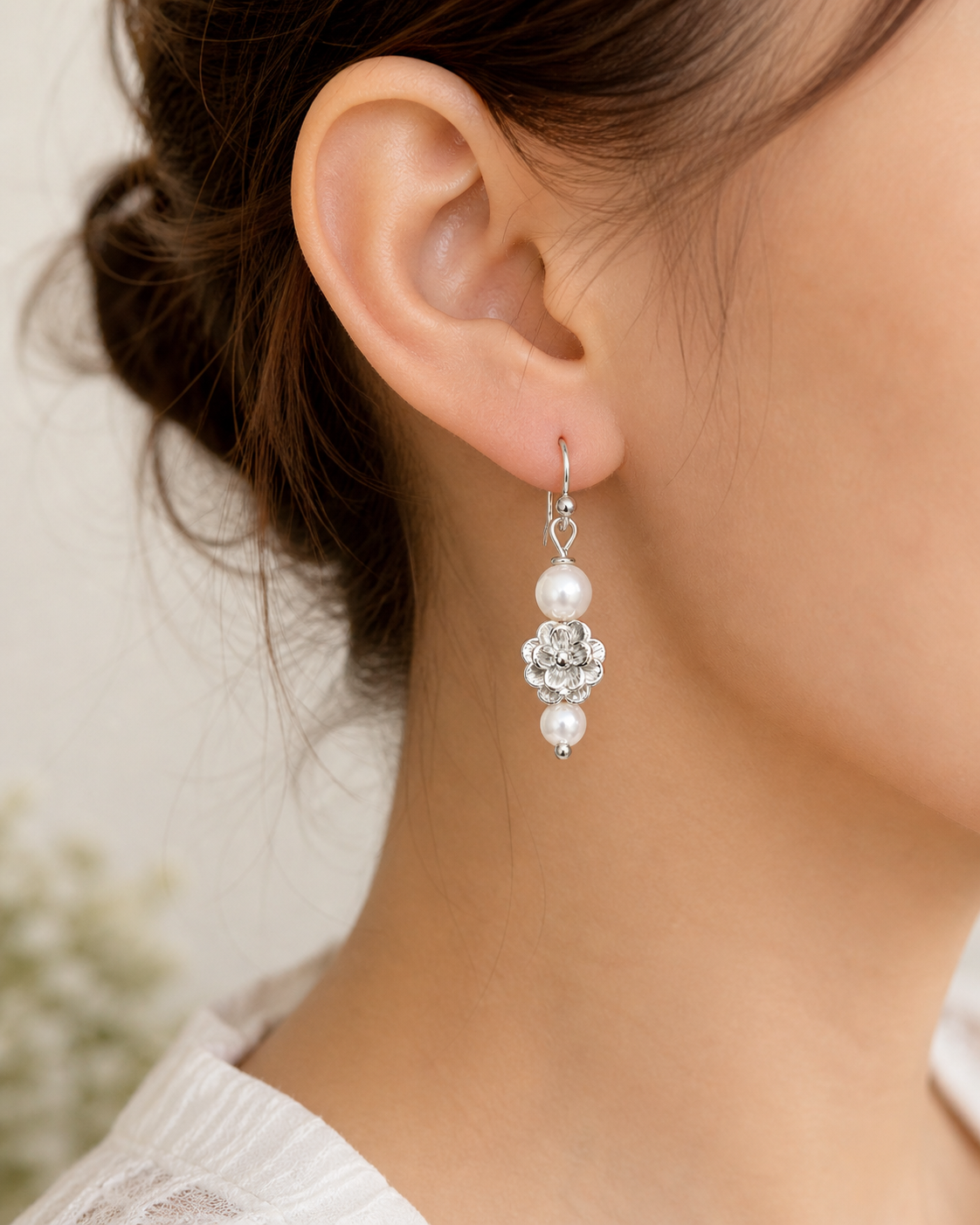 Woman wearing silver floral pearl drop earrings close up lightweight elegant jewelry