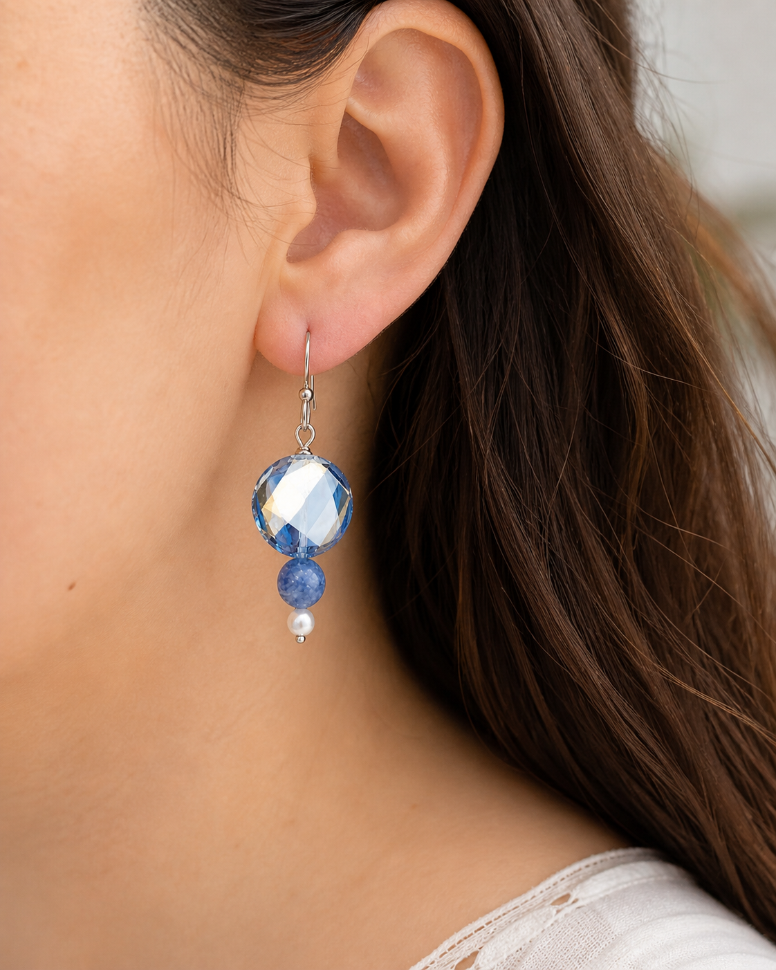 Woman wearing blue drop earrings with pearl detail close up lightweight jewelry