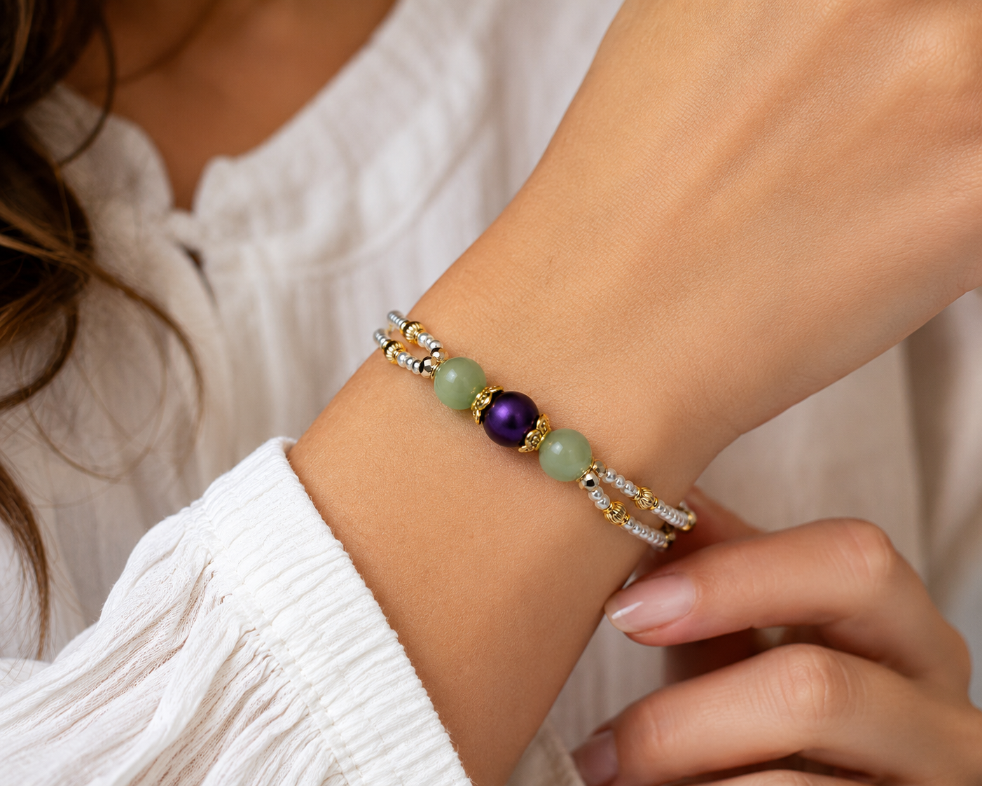 Woman wearing delicate double-strand pearl bracelet with green accent beads and purple centerpiece in elegant lifestyle jewelry photo