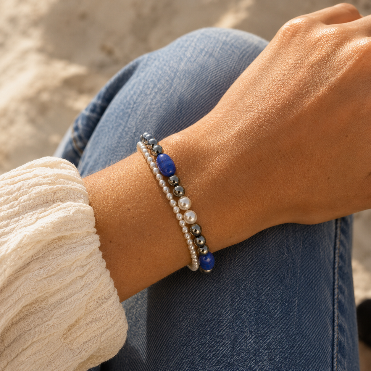 Worn - Handmade blue, pearl, and hematite dual strand bracelet worn on wrist in natural sunlight with casual elegant styling.