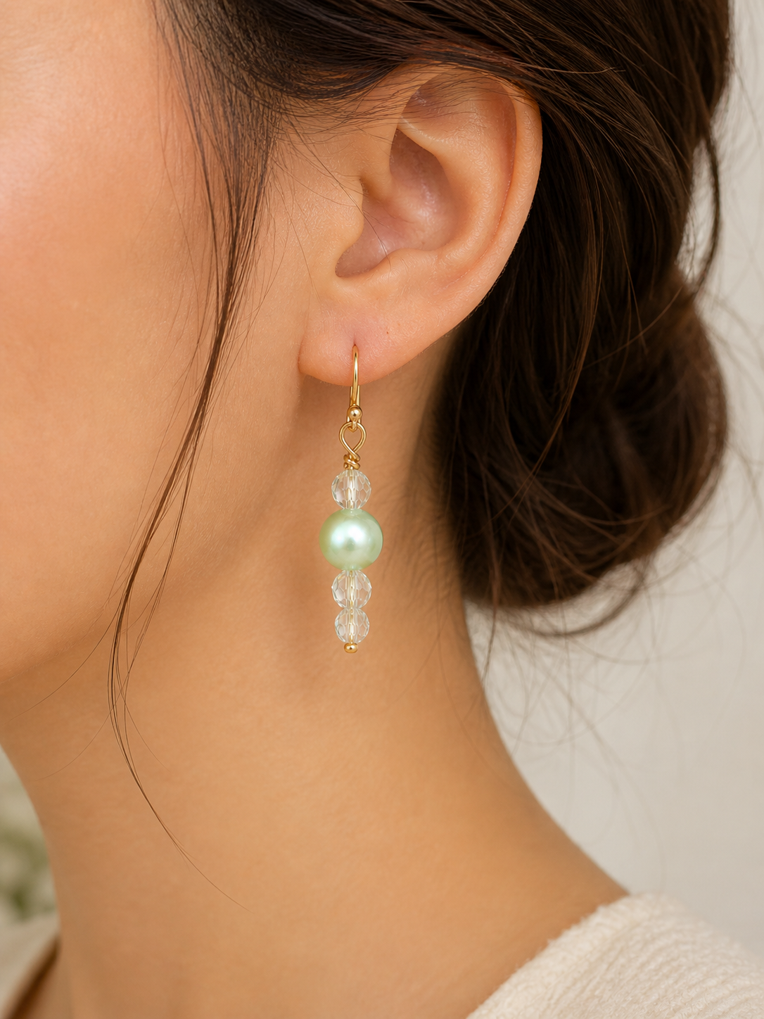 Woman wearing mint green pearl drop earrings with crystal beads close up lightweight elegant jewelry