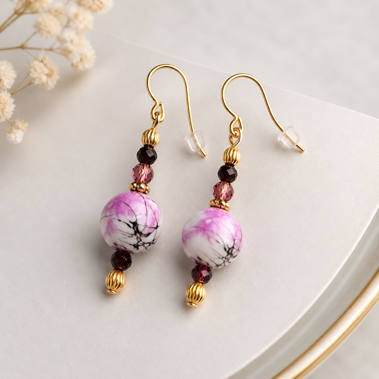 Pink marble earrings styled on neutral background with gold accents