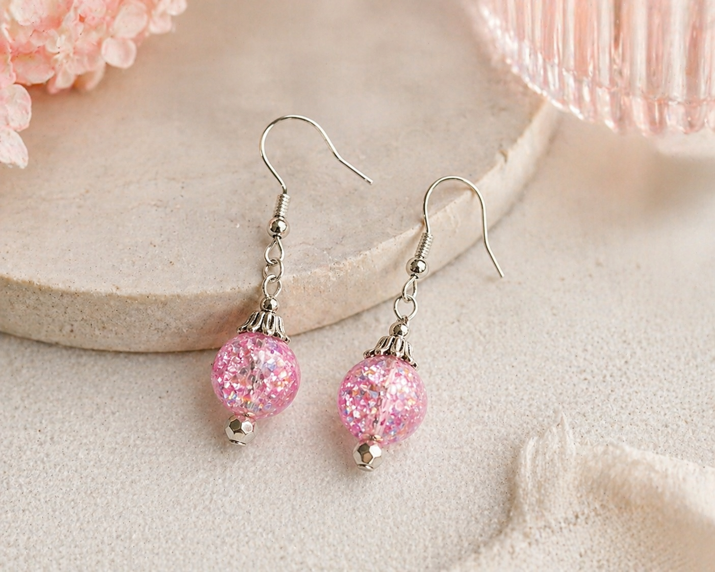 Pink glitter bead earrings styled on soft neutral background