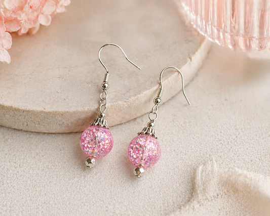 Pink glitter bead earrings styled on soft neutral background